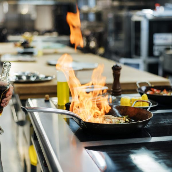 vista-lateral-del-chef-flameando-un-plato-en-la-cocina